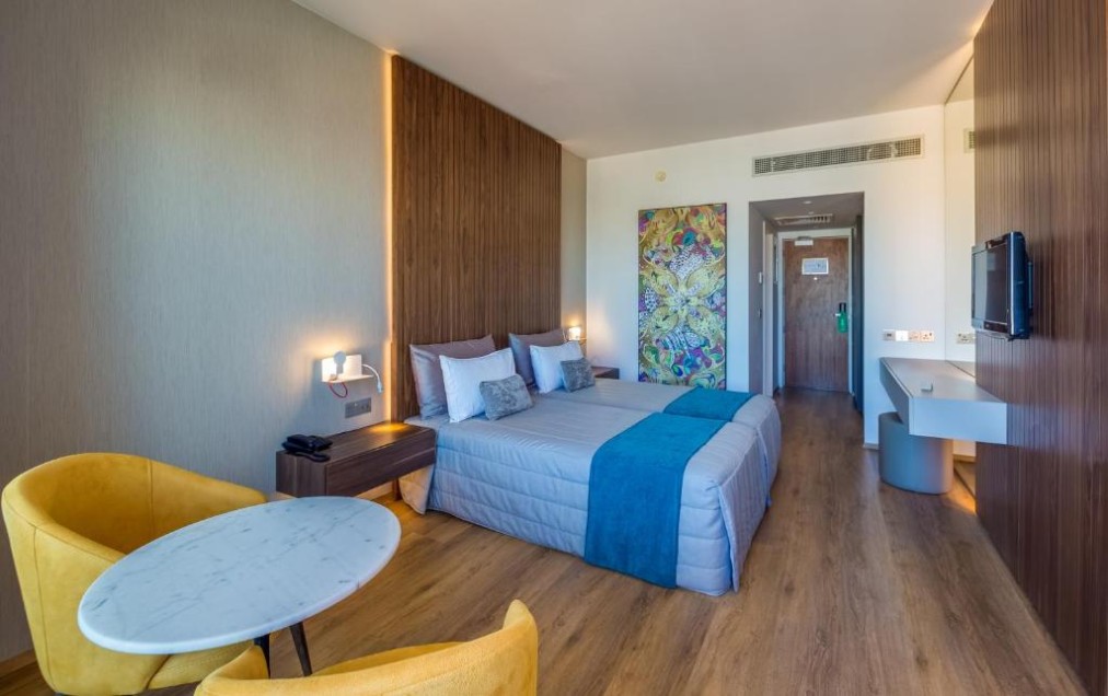 Gästezimmer mit Doppelbett, Sitzbereich und wandmontiertem Fernseher.