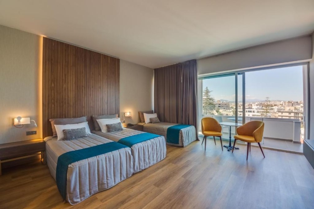 Gästezimmer mit zwei Betten, Schlafsofa und Sitzbereich am Balkon.