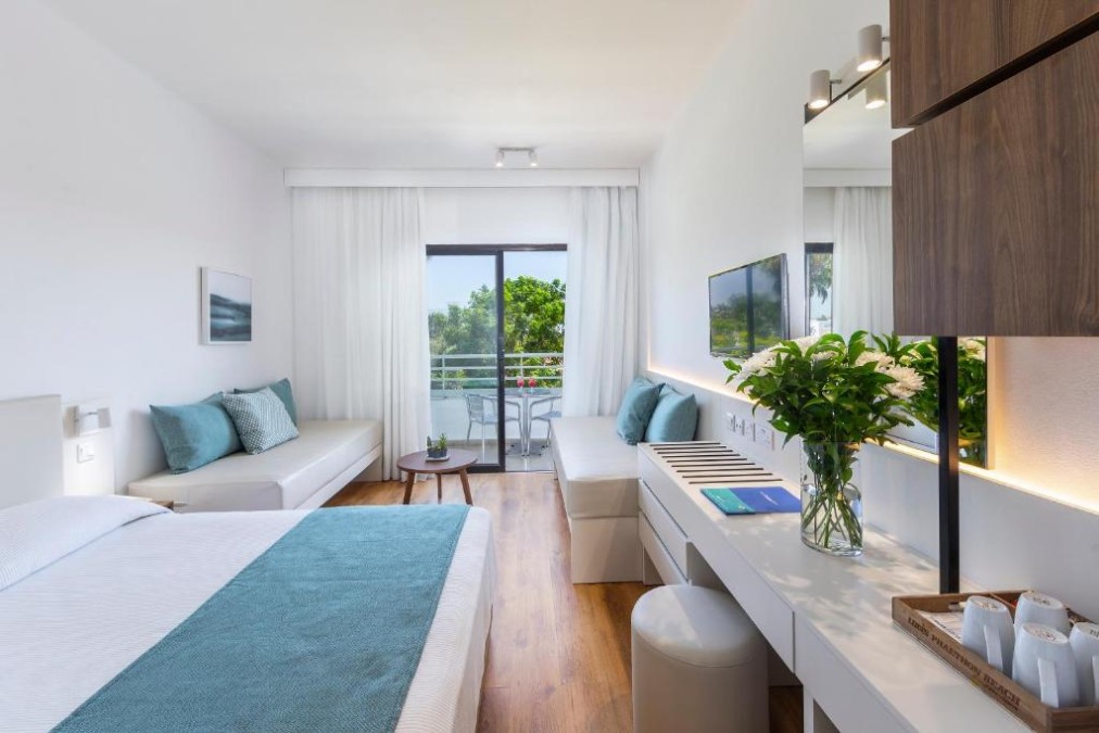 Helles Gästezimmer mit Schreibtisch, Sofas und Balkonblick.