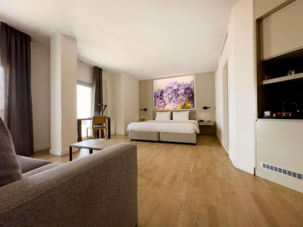 Geräumiges Zimmer im Suite-Stil mit Doppelbett, Sofa, Tisch und Holzboden.