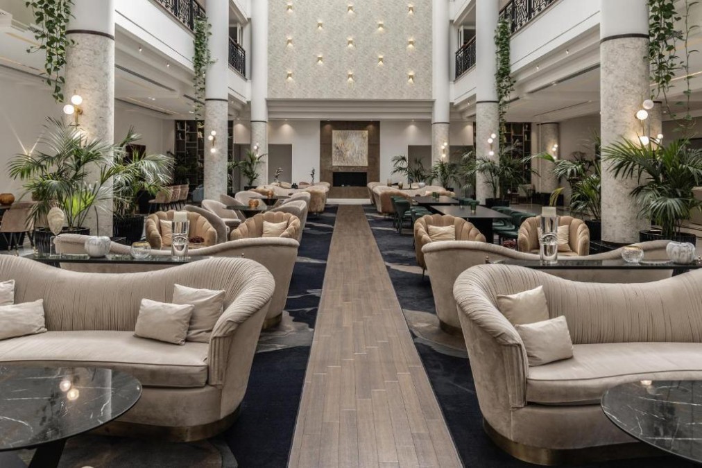 Hotellobby mit Sofas, Marmorsäulen und zentralem Kamin.