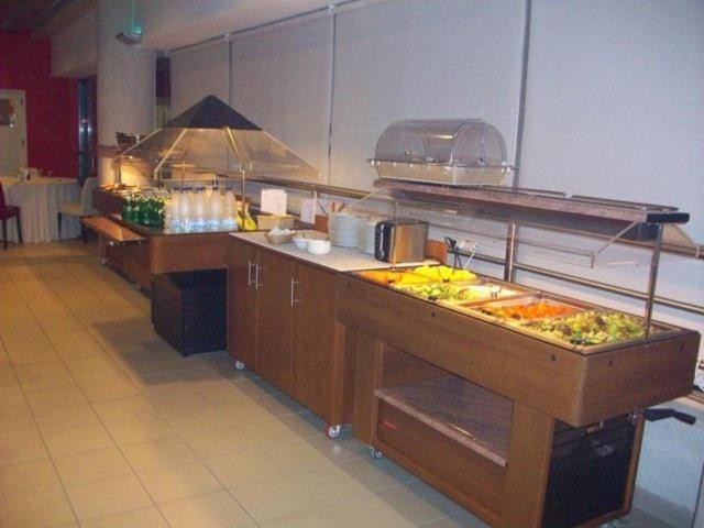 Comptoir buffet en libre-service avec salades, plats chauds et boissons disposés sur des tables en bois