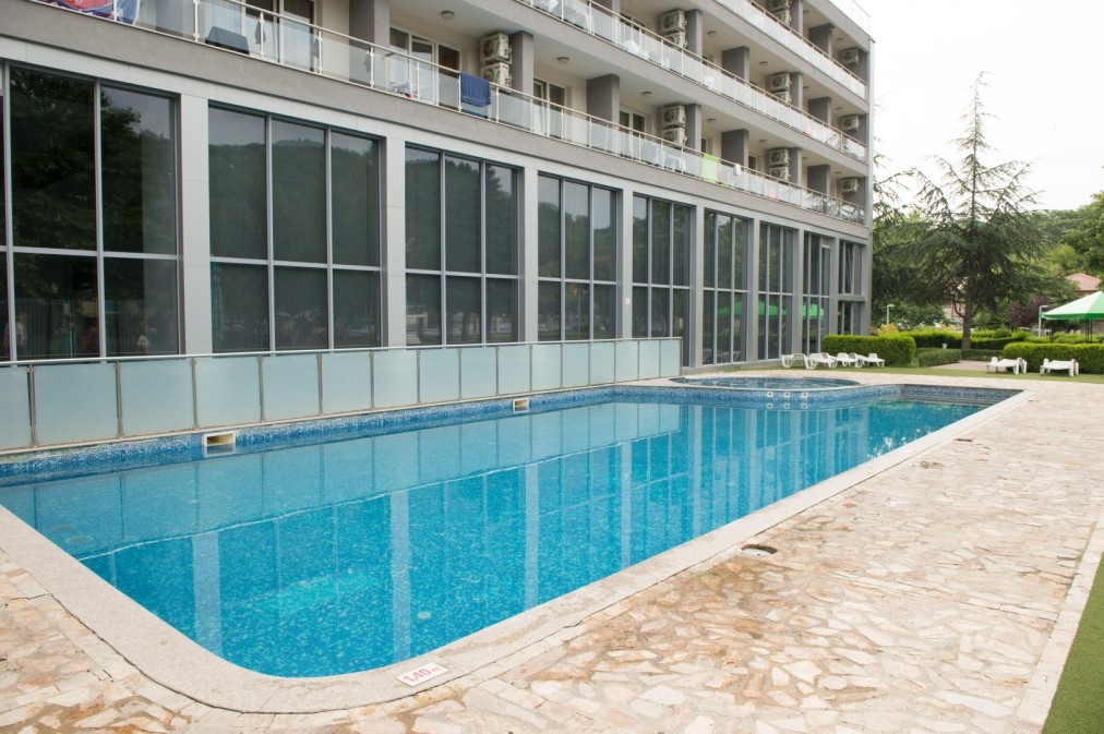 Piscine extérieure rectangulaire à côté de la façade de l'hôtel et de la terrasse, adaptée pour la récupération après les entraînements