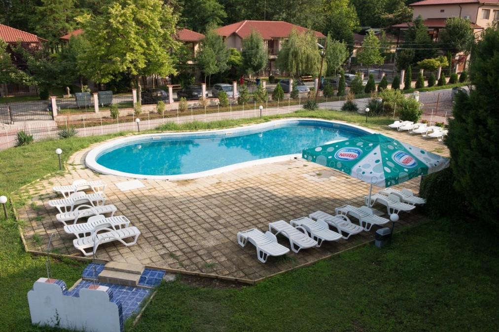 Piscine de jardin avec chaises longues et parasols, utilisée pour la récupération des athlètes pendant les séjours en stage