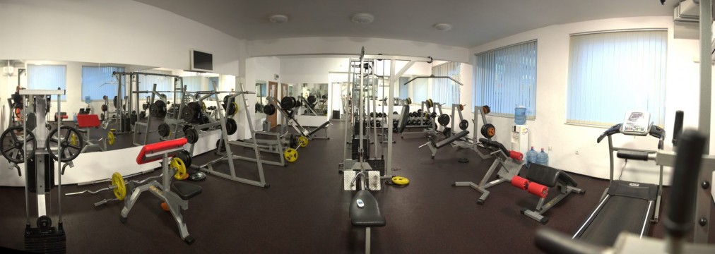 Vue large d'une salle de gym entièrement équipée avec bancs et machines pour le conditionnement en stage d'entraînement