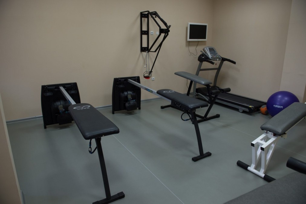Petite salle d'entraînement avec bancs, tapis de course, espaliers et ballons d'exercice pour les entraînements des athlètes