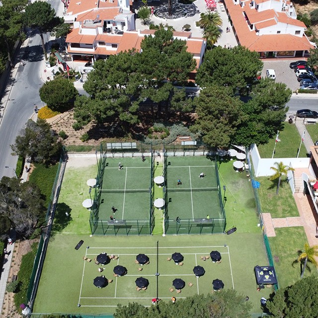 Vue aérienne de courts de tennis avec club-house et parasols d'assise.