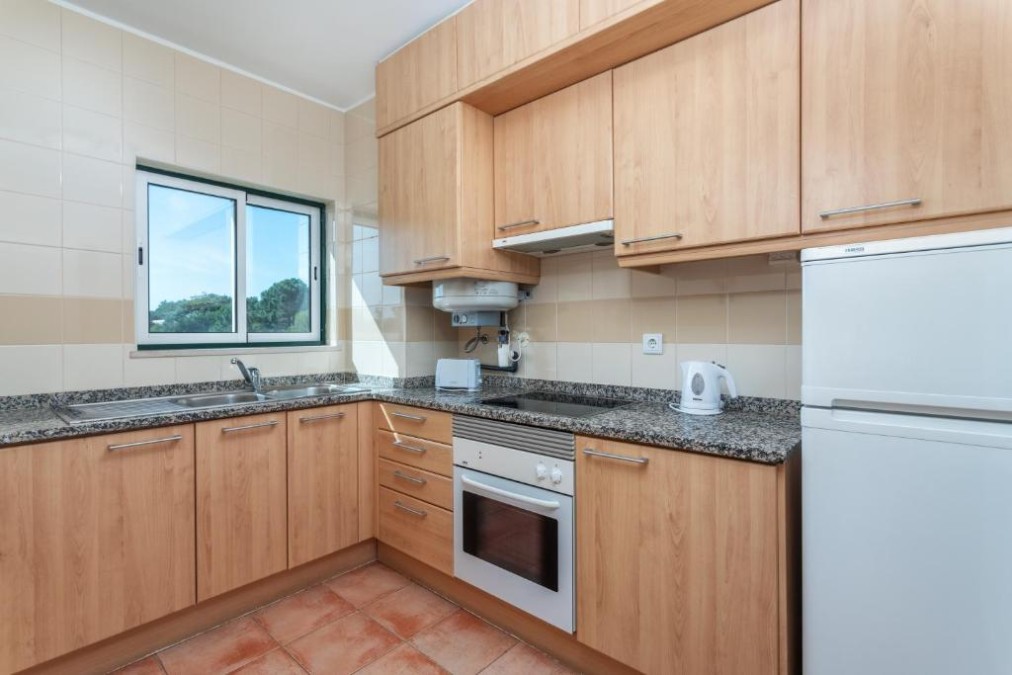 Kitchenette d'appartement avec four, réfrigérateur et plan de travail.