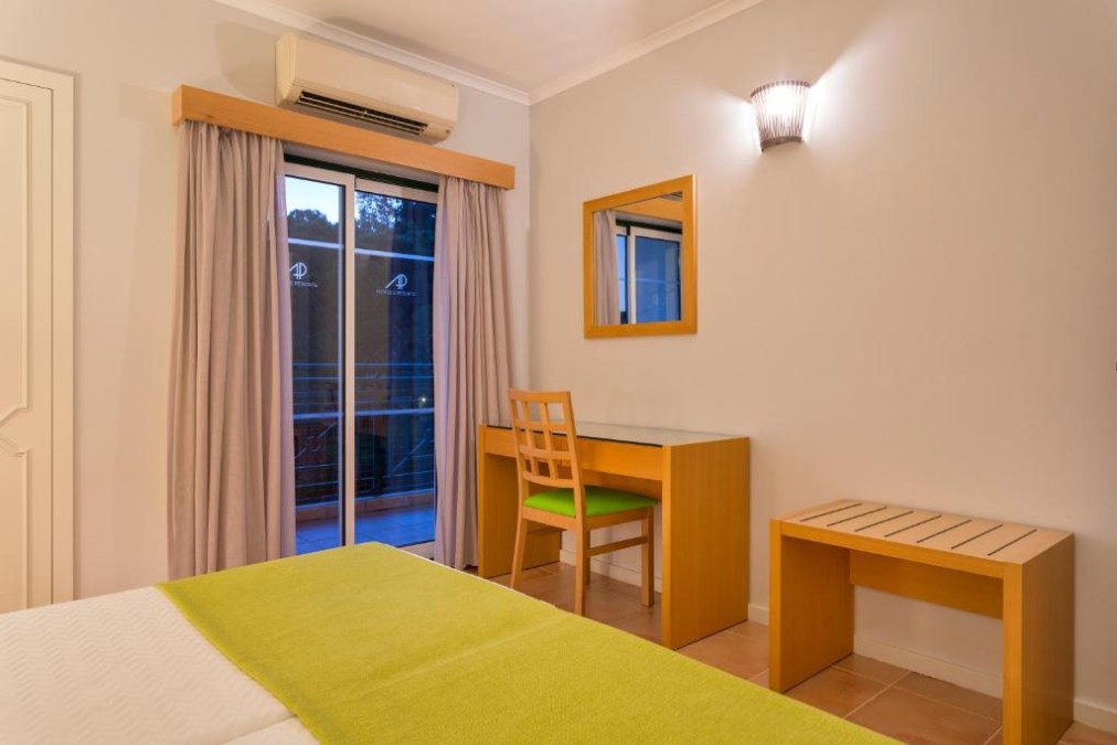 Chambre d'hôtes avec lit, bureau et porte-fenêtre donnant sur le balcon.