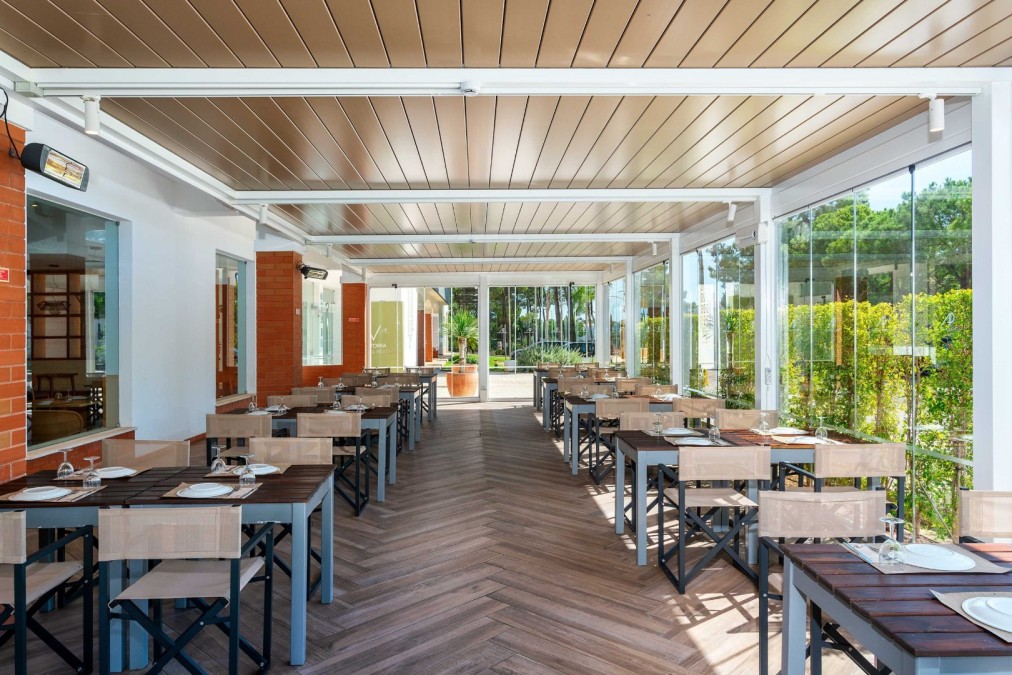 Terrasse couverte avec tables dressées et parois vitrées.