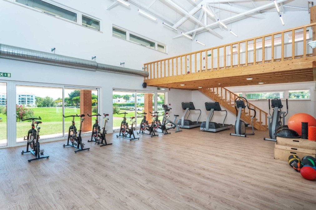 Salle de sport lumineuse avec vélos de spinning, tapis de course et équipements de conditionnement pour stages d'entraînement.