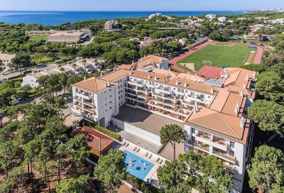 Vue aérienne du complexe au bord de la mer avec piste d'athlétisme et terrain de football.