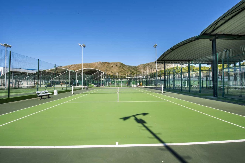 Courts de tennis extérieurs avec clôtures et toits partiels.