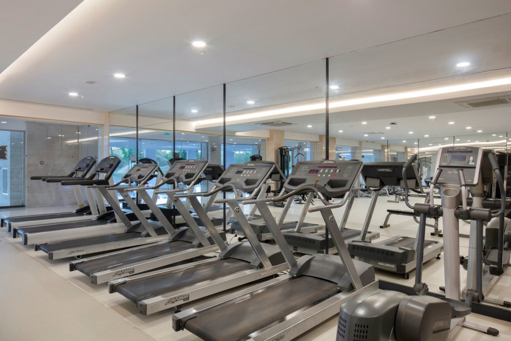 Zone cardio de la salle de fitness avec tapis de course et vélos elliptiques