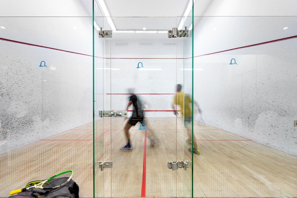 Deux athlètes jouant au squash sur un terrain intérieur vitré lors d'une séance d'entraînement