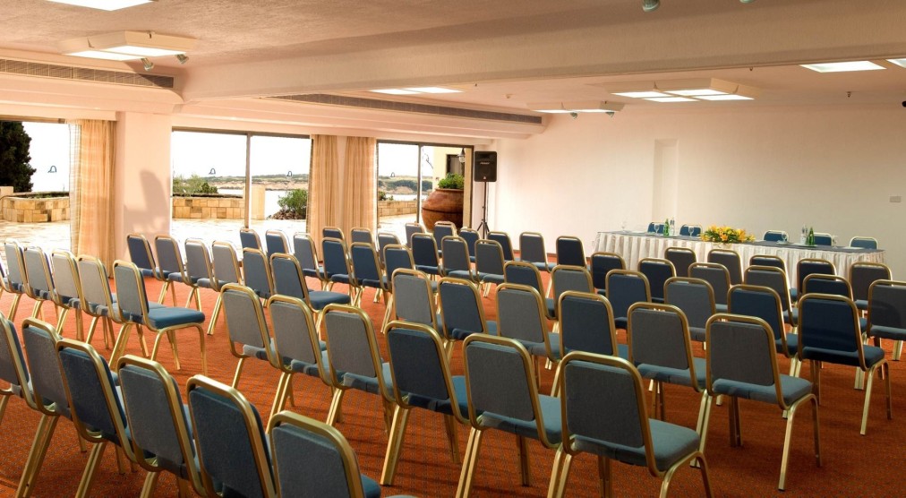 Salle de conférence avec rangées de chaises bleues et table en façade pour séminaires ou ateliers d'équipe