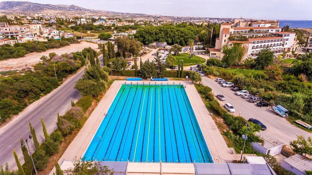 Vue aérienne d'une piscine olympique avec parking et paysage en arrière-plan