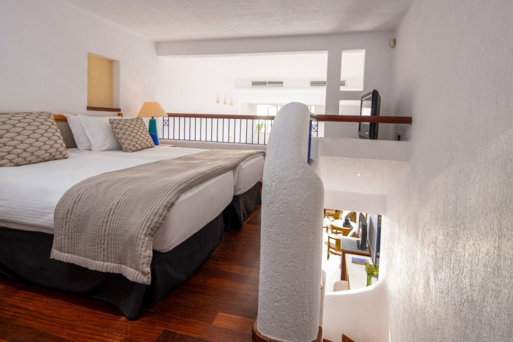 Chambre d'hôtel de style loft avec lits jumeaux en mezzanine et escalier en contrebas