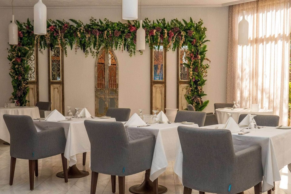 Salle à manger élégante avec nappes blanches, chaises grises et décoration florale pour les repas d'équipe