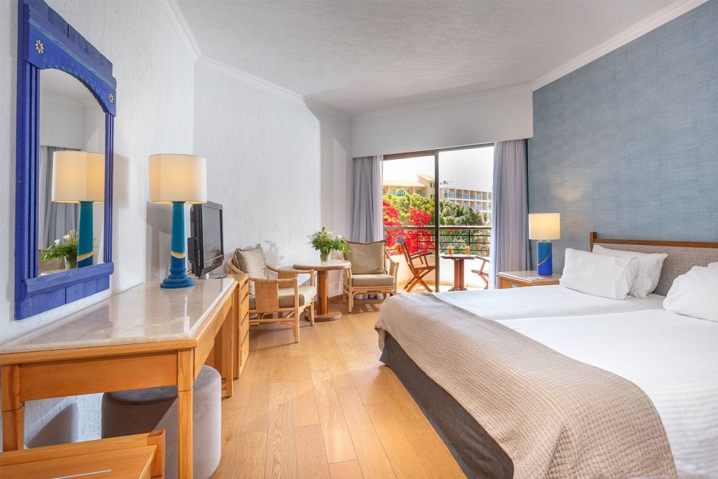 Chambre moderne avec mur d'accent bleu, balcon et espace de travail pour les participants au stage sportif