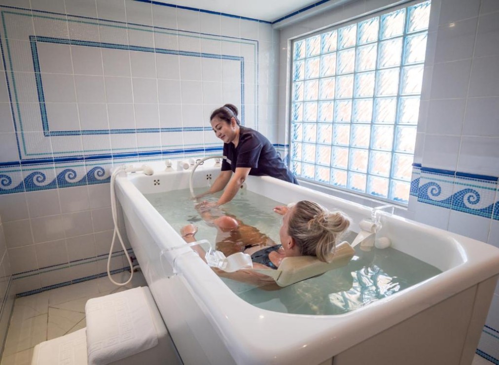 Séance de bain d'hydrothérapie avec thérapeute assistant un client, adapté pour rééducation et récupération