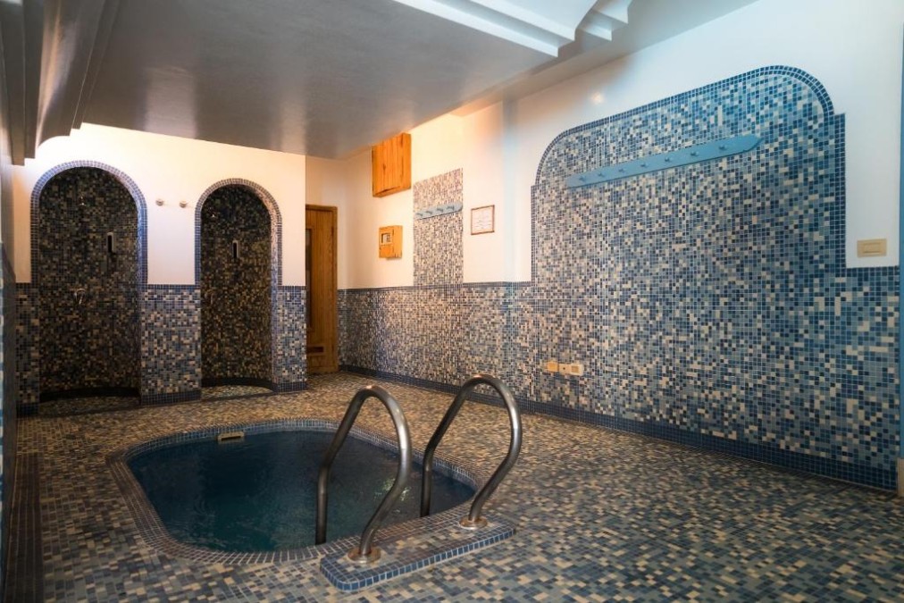 Petit espace jacuzzi/hammam carrelé avec murs en mosaïque et alcôves de douche pour récupération et relaxation