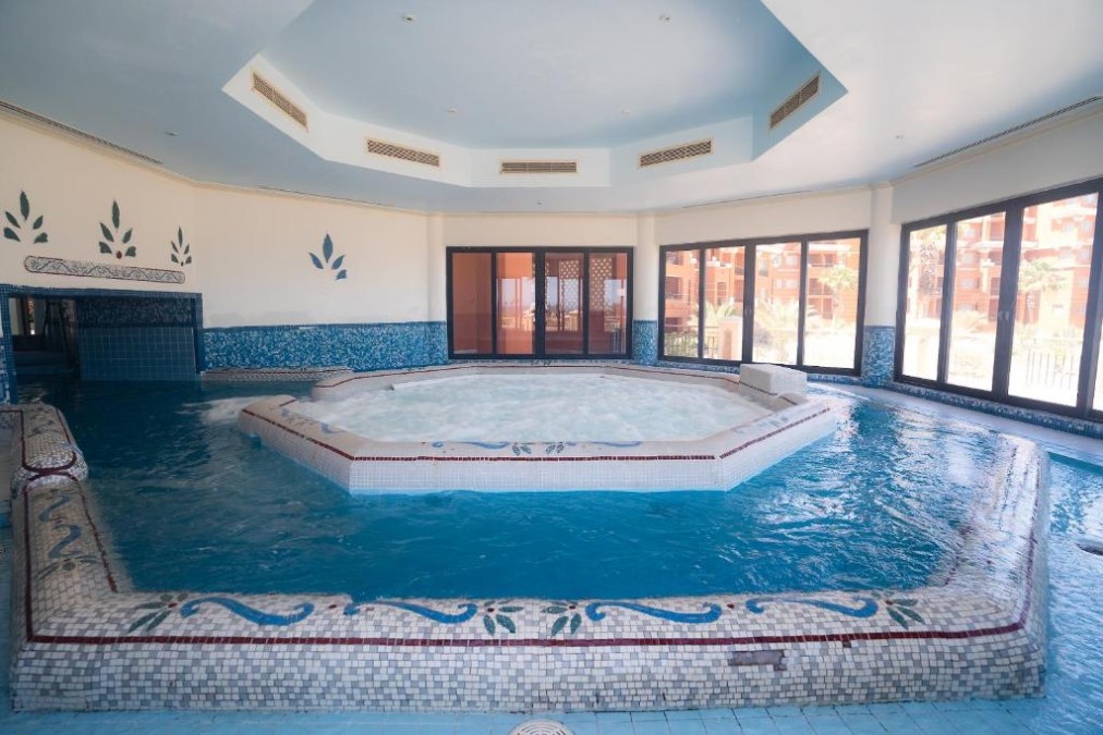 Piscine spa intérieure avec plateforme jacuzzi centrale et fenêtres panoramiques, idéale pour récupération post-entraînement
