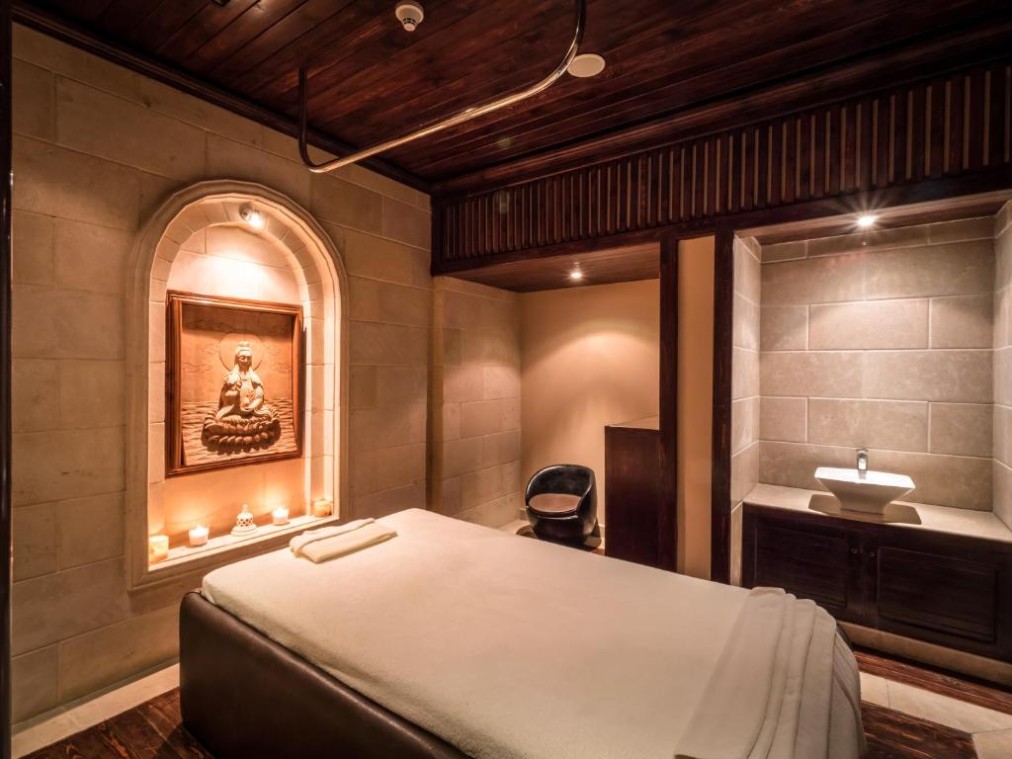 Salle de soins spa chaleureuse avec lit de massage, bougies et décor relaxant pour séances de récupération