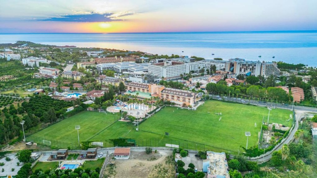 Vue aérienne au coucher du soleil du complexe et d'un terrain de football surplombant la mer.
