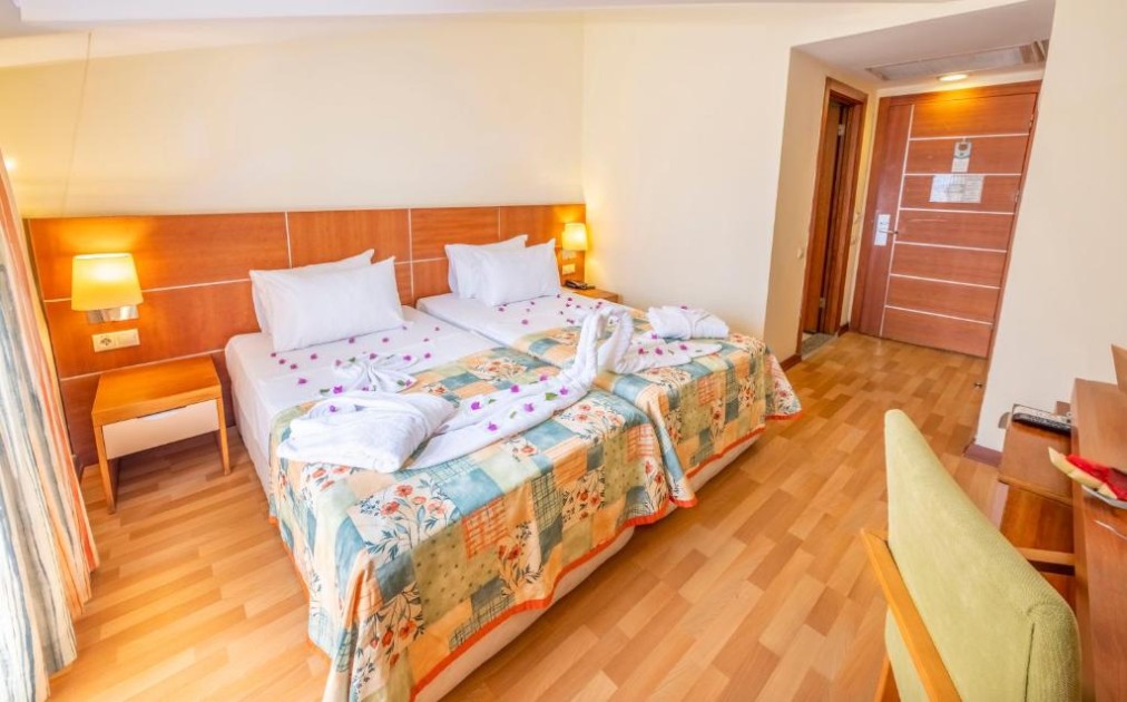 Chambre twin avec deux lits simples, lampes de chevet, bureau et parquet.