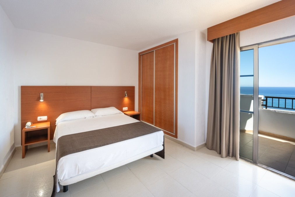 Chambre double avec accès au balcon, armoire et vue sur la mer.