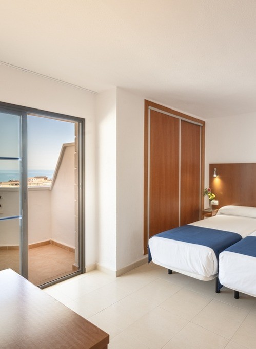 Chambre twin avec accès au balcon et vue partielle sur la mer.