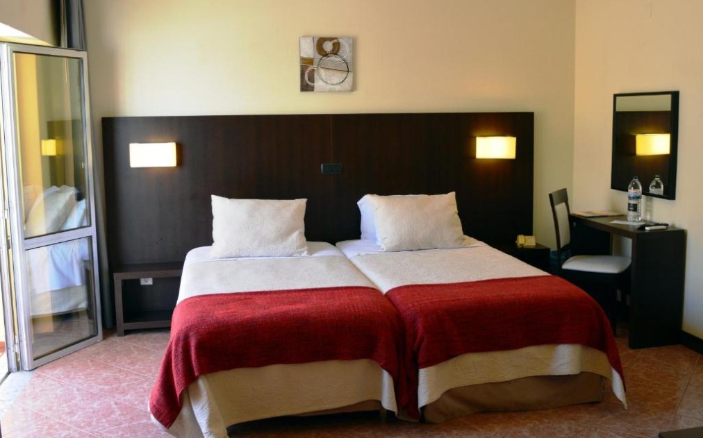 Chambre twin avec bureau, miroir et porte-fenêtre ouverte sur le balcon.