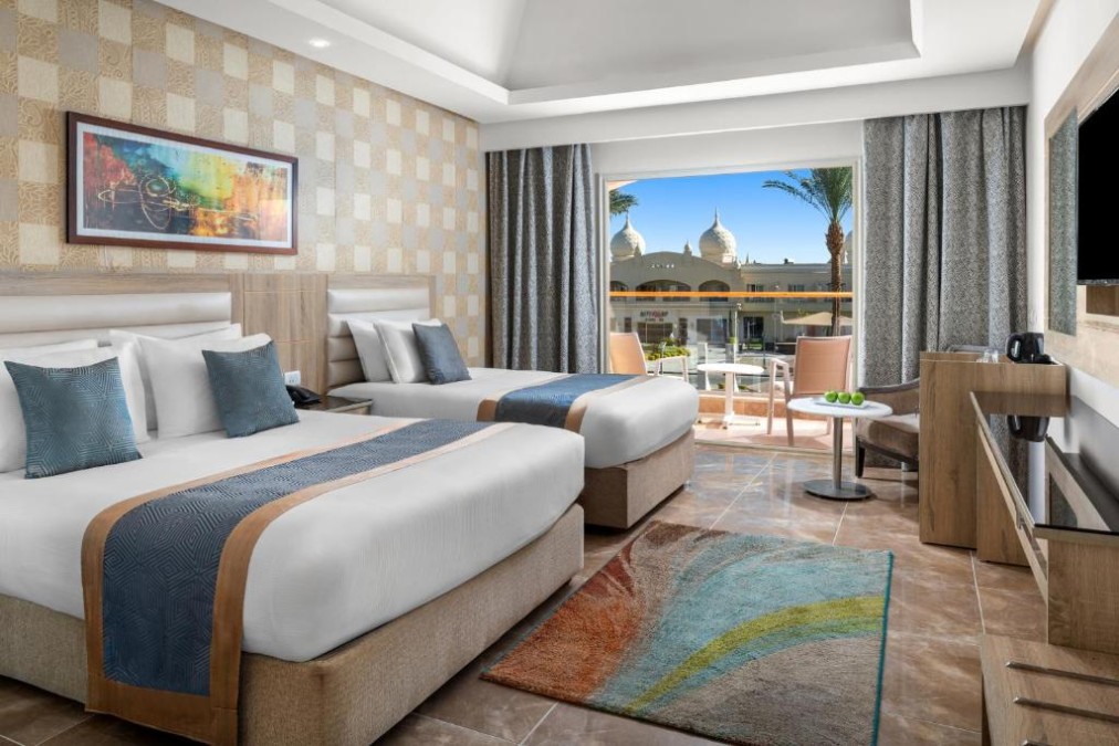 Chambre twin avec deux lits simples et coin salon sur le balcon, aménagée pour un séjour de stage sportif.
