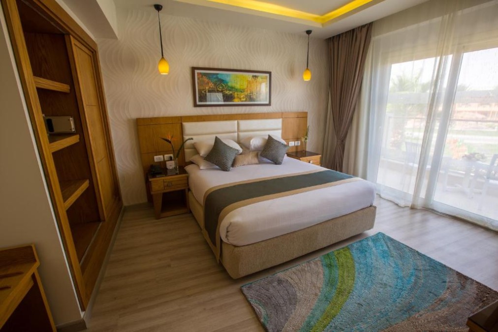 Chambre double lumineuse avec un grand lit, une armoire et des portes coulissantes donnant sur un balcon/terrasse.