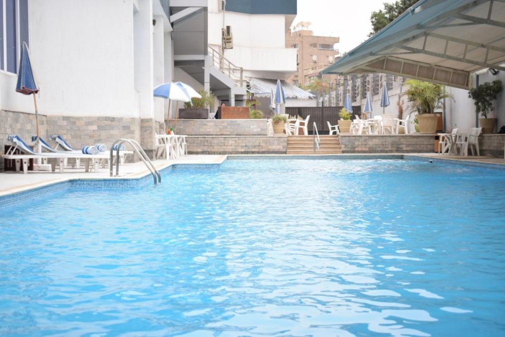 Piscine extérieure avec chaises longues, parasols et sièges au bord de la piscine.