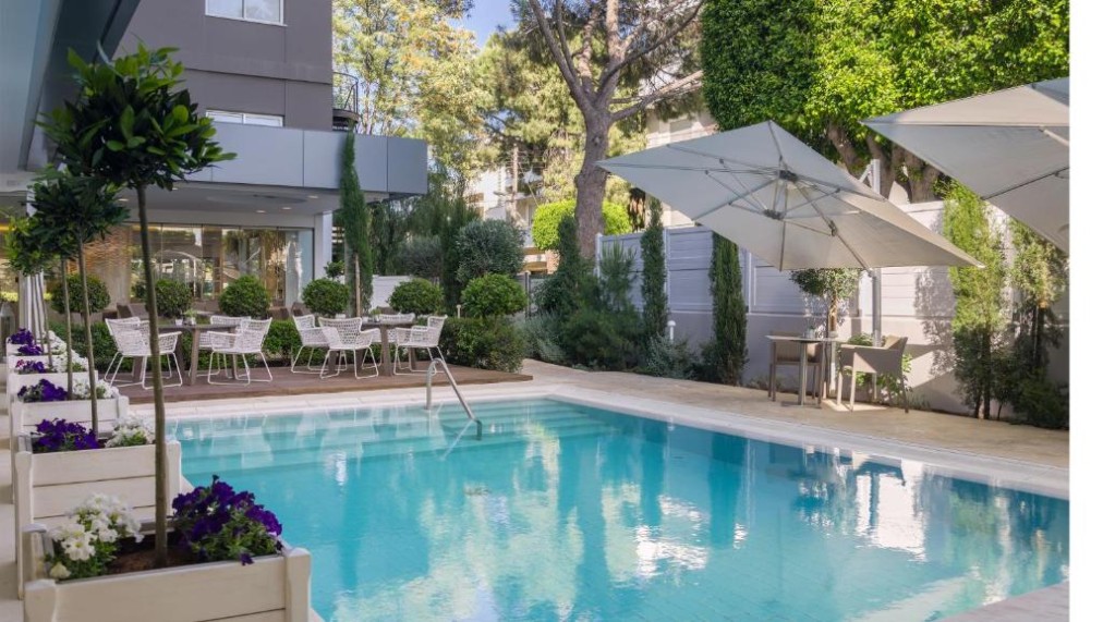 Piscine extérieure avec terrasse environnante, parasols et sièges de jardin.